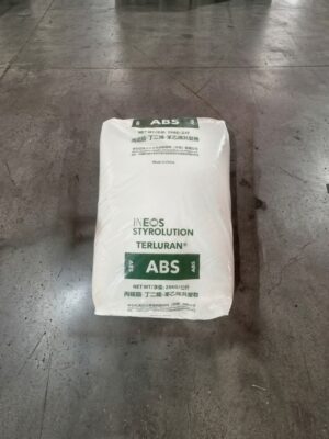 A bag of cement rests on the floor of a warehouse, surrounded by industrial shelving and concrete walls