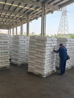 A man stands in front of a large pile of white bags labeled STL GPPS 525