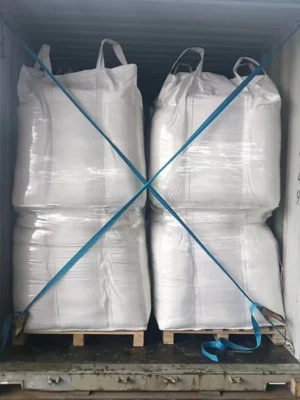 A construction worker loads 4 large bags of white sand into a container for transport A construction worker loads 4 large bags of white sand into a container for transport