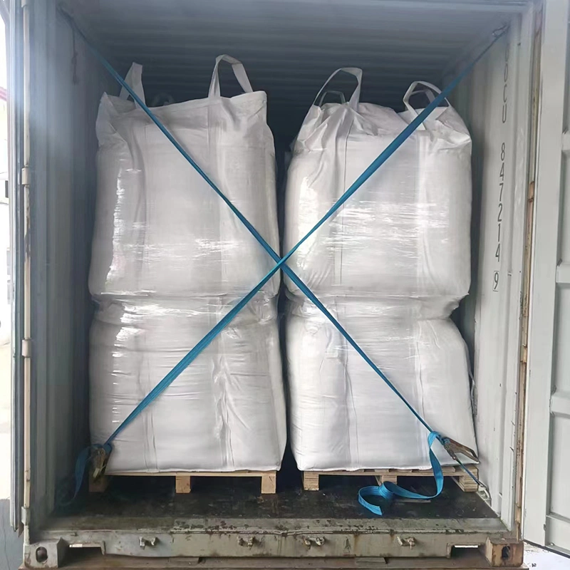 A construction worker loads 4 large bags of white sand into a container for transport