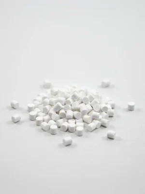 Pequeños gránulos blancos opacos de masterbatch CAM-205 sobre un fondo blanco limpio